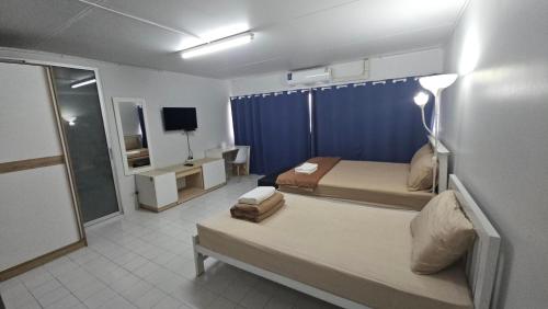 a bedroom with two beds and a blue curtain at New Room in Nonthaburi