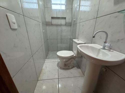 a white bathroom with a toilet and a sink at Pousada AMD in Florianópolis