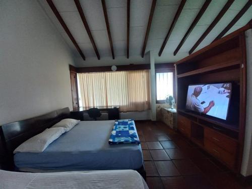 a bedroom with a bed and a flat screen tv at El Linaje Home in Cali