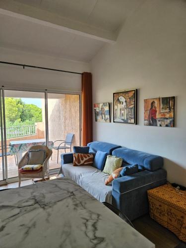 un salon avec un canapé bleu et un balcon dans l'établissement Mazet, à Cavalaire-sur-Mer