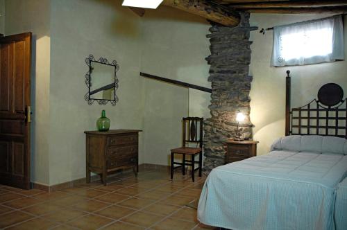 a bedroom with a bed and a stone wall at Los Balcones del Río in Robledillo de Gata