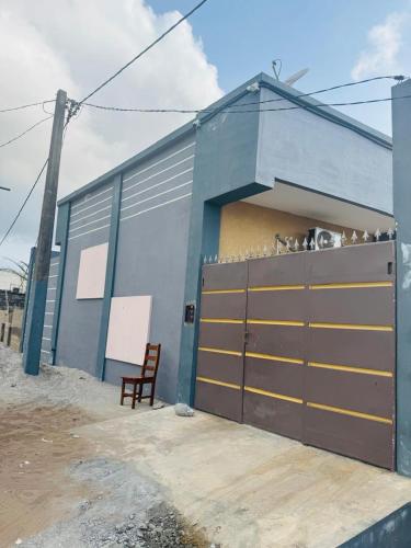 un edificio blu con una porta da garage e una sedia di Les AMAZONES a Cotonou