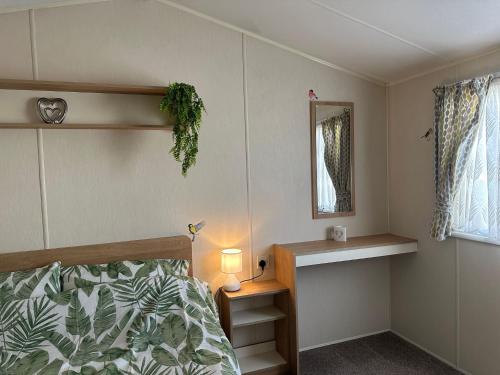 a bedroom with a bed and a mirror and a window at Cosy static caravan in rye! in Rye