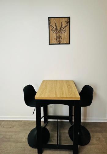 une table en bois avec deux chaises et une photo sur le mur dans l'établissement Studio cosy plein centre & parking à proximité, à Poitiers