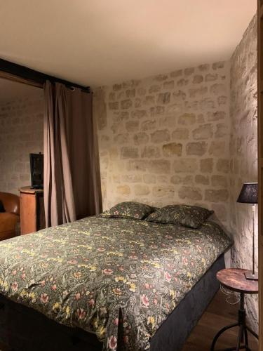 une chambre avec un lit et un mur en pierre dans l'établissement Loft Parisien, à Paris