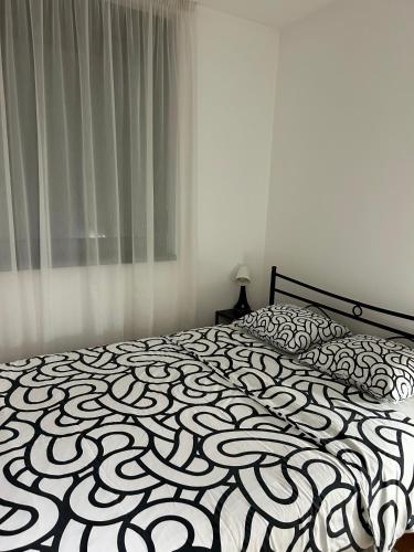 a bedroom with a bed with a black and white comforter at SilverSea Apartman in Šabac