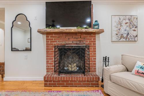a living room with a brick fireplace with a mirror at Southern Pines Gem with 2 Master-King Suites in Southern Pines