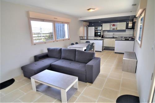 un salon avec un canapé et une cuisine dans l'établissement Maison Indépendante Climatisée à Deux Pas des Plages, Confort et Détente Assurés, à Royan