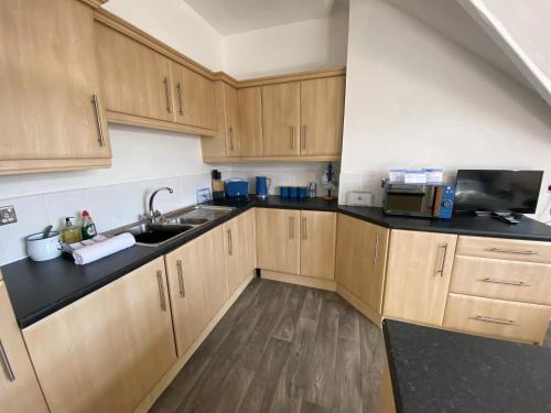 a kitchen with wooden cabinets and a sink and a microwave at Blue Ocean Seaview Penthouse Perfectly Saltburn in Saltburn-by-the-Sea