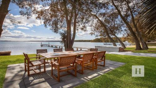 a wooden table and chairs sitting next to a lake at Enjoy Lazy Daze in Summerland Point