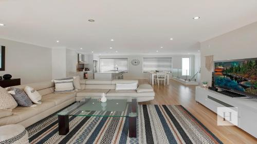 a living room with a couch and a glass table at Enjoy Lazy Daze in Summerland Point