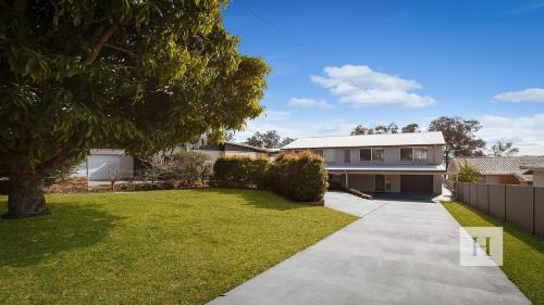 a house with a grass yard and a driveway at Enjoy Lazy Daze in Summerland Point
