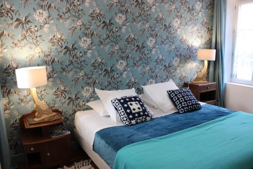 - une chambre dotée d'un lit avec des draps bleus et du papier peint floral dans l'établissement La Georginette, à Saint-Georges-sur-Cher