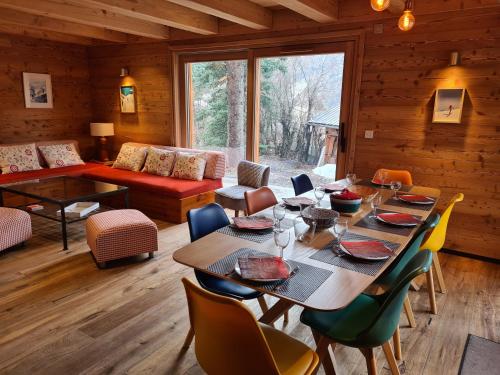 une salle à manger avec une table, des chaises et un canapé dans l'établissement Chalet neuf Eterlou 130 m carrés 5 chambres 10 couchages à Serre Chevalier, à Saint-Chaffrey