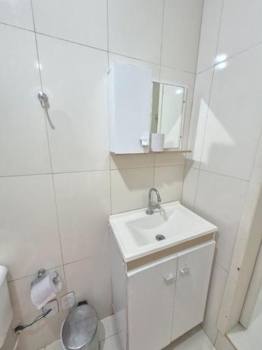 a white bathroom with a sink and a mirror at Pousada Cantinho da Tia Sandra in São Francisco do Sul