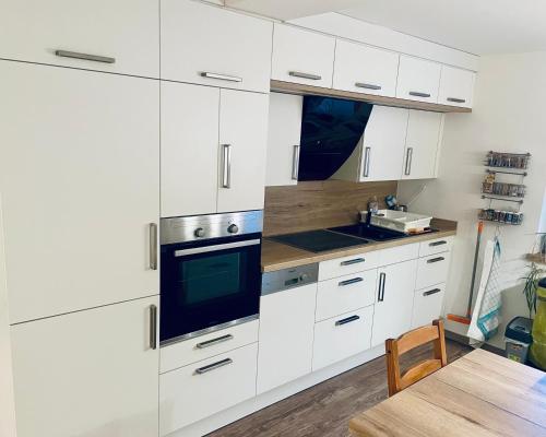 a kitchen with white cabinets and a sink and a table at Moderne Wohnung mit großer Küche und Bad in Stadtilm