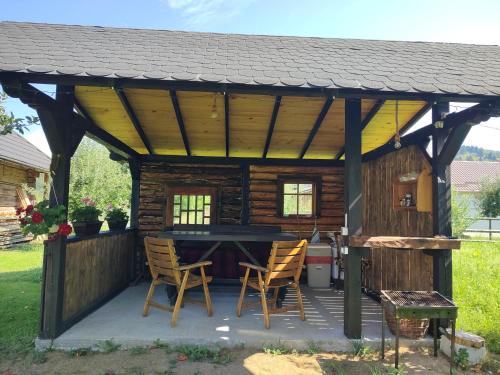 einen Holzpavillon mit einem Tisch und Stühlen in der Unterkunft La căsuța cu amintiri in Vama