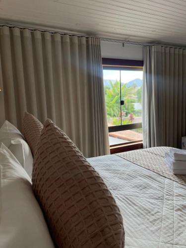 a bedroom with a bed with a large window at Pousada Villa Tiradentes Suítes - Centro in Tiradentes