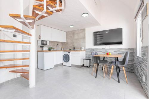 a kitchen with a table and a tv on a wall at Private Jacuzzi & vista al mar in Mogán