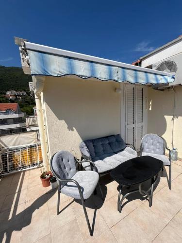 a patio with a couch and chairs on a balcony at PRCPORTOapartmani in Herceg-Novi