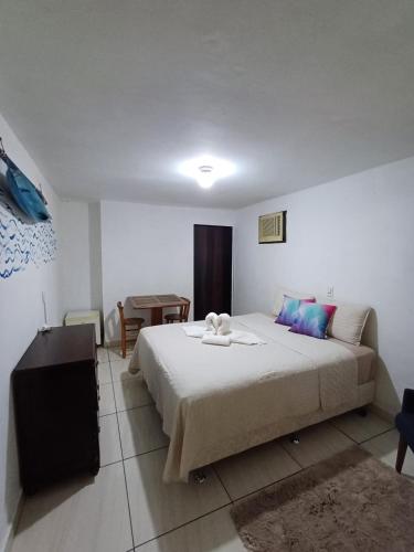 a bedroom with a large bed and a table at Suite Térrea in Bombinhas
