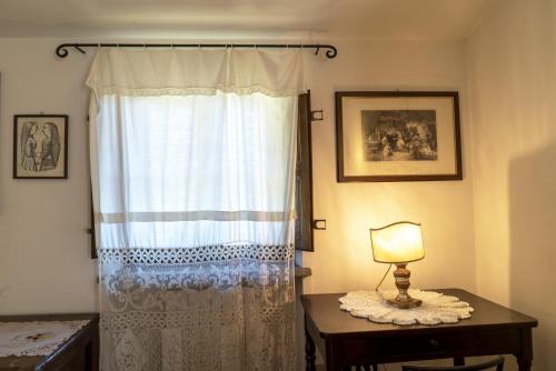 a bedroom with a curtain and a table with a lamp at Country Historical House Lucca in San Gennaro