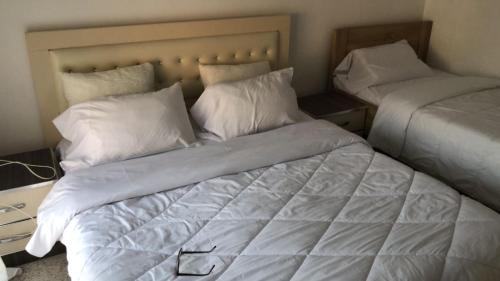 a bedroom with two beds with white sheets and pillows at Kris's Studio in Lezhë