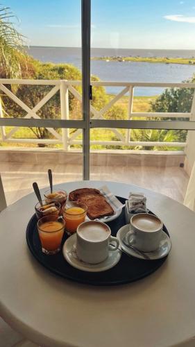 een dienblad met eten op een tafel met twee kopjes koffie bij Marina del Faro Resort in Termas de Río Hondo