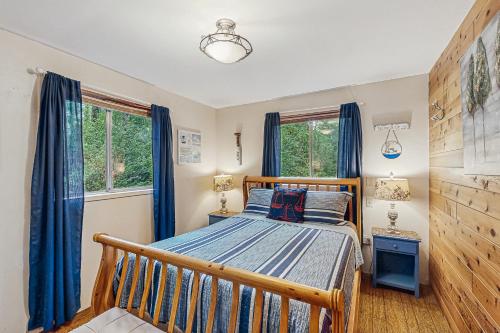 a bedroom with a wooden bed with blue curtains at Sabala Cabin in Randolph