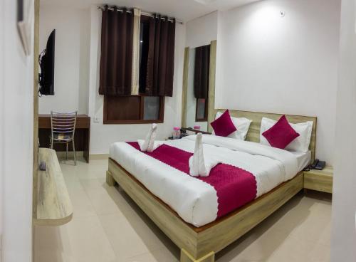 a bedroom with a large bed with red and white pillows at Hotel Neu-Nest inn in Rishīkesh
