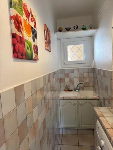 une petite salle de bain avec un lavabo et une fenêtre dans l'établissement L'helios studio au calme centre et mer, à Vallauris