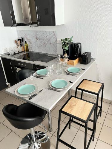 a table with plates and chairs in a kitchen at Montbel'appart - Charmant appart T1 tout équipé in Montbéliard