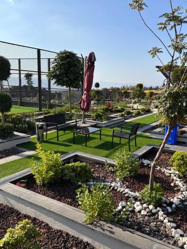 a park with benches and an umbrella in the grass at Kinda vip in Al Mashāriqah