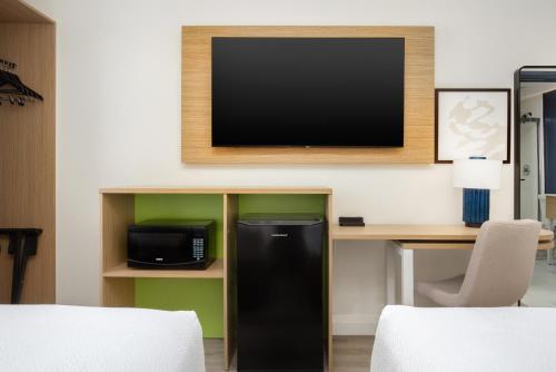 a room with a black refrigerator and a tv on a wall at Spark by Hilton Brockville in Brockville