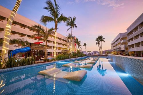 a swimming pool with lounge chairs in a resort at Emporio Mazatlan in Mazatlán
