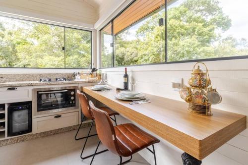 a kitchen with a wooden table and chairs and windows at Vivenda Le Vin em Alfredo Wagner in Barracão