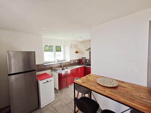 une cuisine avec des placards rouges et une table en bois dans l'établissement Ty Kerveguen, à Plougoulm