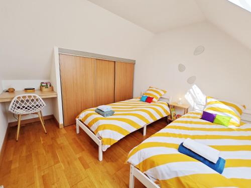 - une chambre avec 2 lits et un bureau avec une chaise dans l'établissement Ty Kerveguen, à Plougoulm