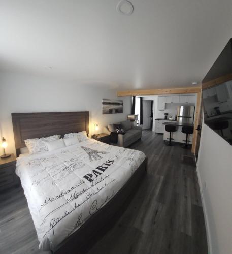 a bedroom with a large bed with white sheets at Auberge Le Cosy Amos in Amos