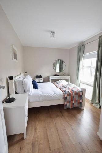 a bedroom with a white bed and a wooden floor at Maggies Leap Townhouse in Newcastle