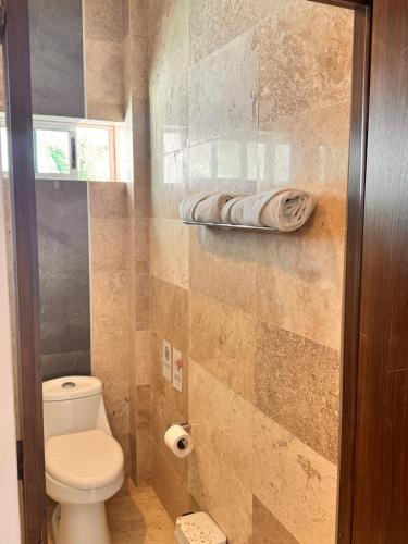a bathroom with a toilet and a towel on a shelf at Hotel TamYanJa in Tamiahua