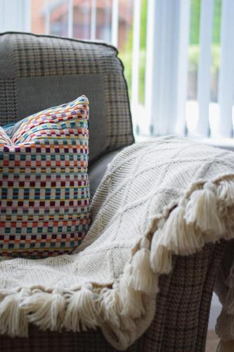 a blanket and a pillow on a wicker chair at Maggies Leap Townhouse in Newcastle