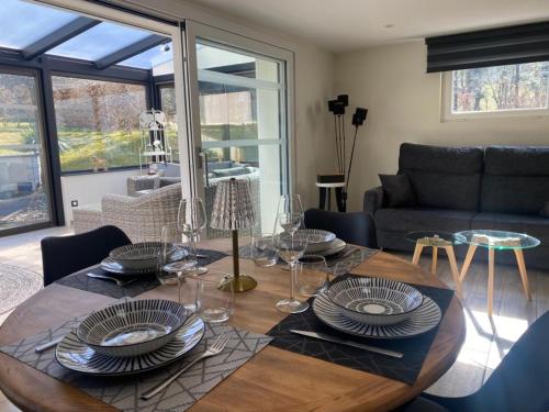 une table en bois avec des assiettes et des verres à vin dessus dans l'établissement Charmant appartement 3* au cœur des Vosges (PMR), à Vecoux