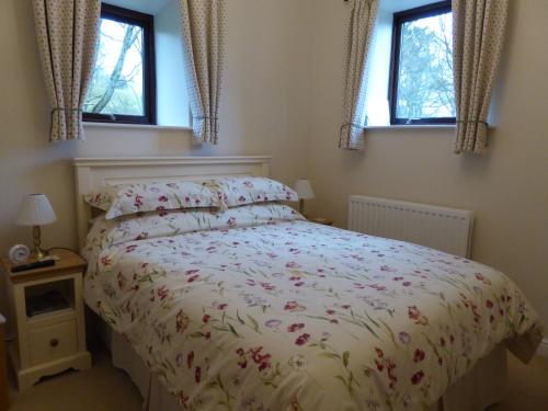 a bedroom with a bed and two windows at Orchard House Bed and Breakfast in Grassington