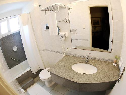 a bathroom with a sink and a toilet and a mirror at Village Hotel in Ponta Grossa