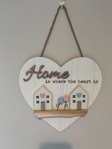 a wooden heart shaped sign with a home is where the heart is at Emville Lodge in Galway