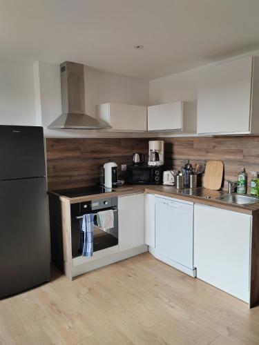 une cuisine avec des armoires blanches et un réfrigérateur noir dans l'établissement Beau T3 coeur village, à Gruissan