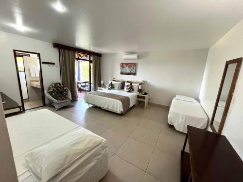 a bedroom with two beds and a table with a chair at Colonna Galapagos Garden Hotel in Búzios