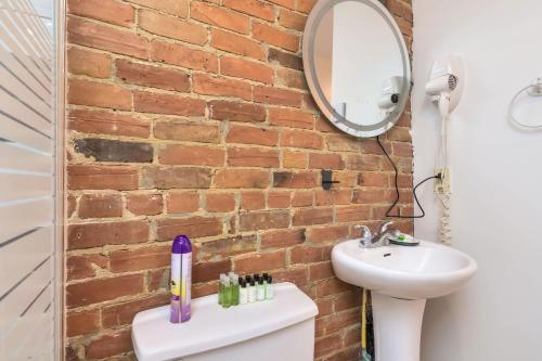 Un baño con lavabo y pared de ladrillo. en Fox Aparthotel Palais Des Congres IV, en Montreal