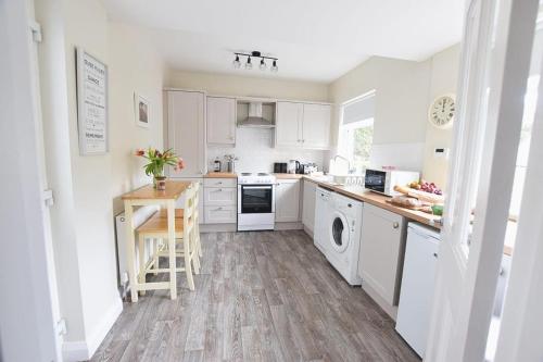 a kitchen with white cabinets and a wooden floor at Maggies Leap Townhouse in Newcastle